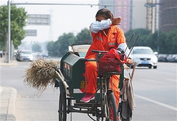 7月9日,大兴天宫院,一名环卫工人边骑环卫车,边擦汗.