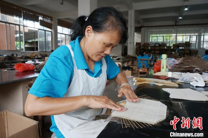 图为邱广初的工人手工制作团扇贴面。　欧惠兰 摄